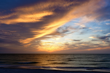 Naklejka na ściany i meble Orange sunset illuminating storm clouds over the Gulf of Mexico at St. Pete Beach, Florida.