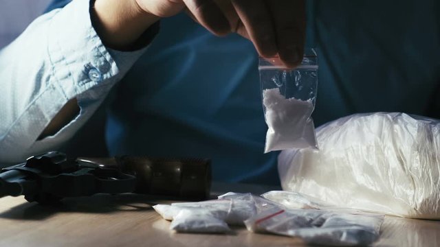 Drug dealer holding a dose of cocaine or heroin in his hands, close-up