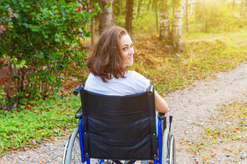 Young happy handicap woman in wheelchair on road in hospital park waiting for patient services....