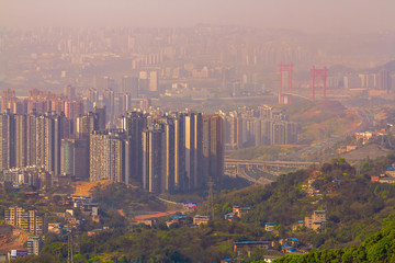 Chongqing, China - March 22, 2018: Blurred cityscape in sunset haze. The bridge across the Yangtze River, residential quarters, mountains dissolved in the haze in the Chinese city of Chongqing. 