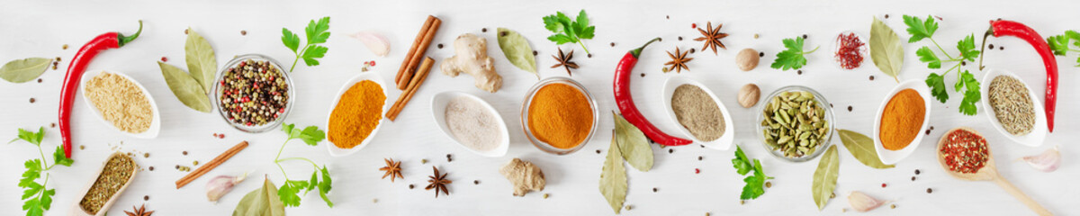 Various assorted colorful spices and herbs on white wooden background top view. Banner size.