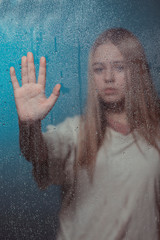 Portrait of a girl through a transparent surface covered with frost