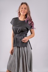 A girl in a dark gray tshirt and light gray skirt, isolated on a white background.