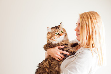 Pretty blonde lady holding cute siberian cat