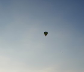 A balloon flies high in the evening sky against a blue sky without clouds on a warm summer evening.