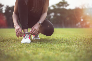 A woman sitting on a shoe before exercising in the park