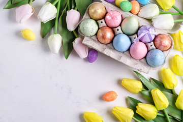 Golden Easter Eggs in box with yellow tulips on stone marble background. Easter background or easter concept.