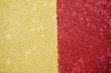 Yellow and red bright soft soft rubber flooring safe for sports and workout or on the playground from the many small round pebbles pressed. Background, texture