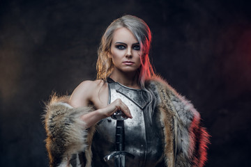 Portrait of a beautiful warrior woman holding a sword wearing steel cuirass and fur. Fantasy...