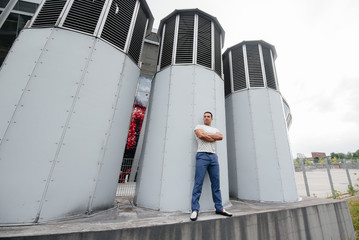 A young man stands in the open air near technical structures
