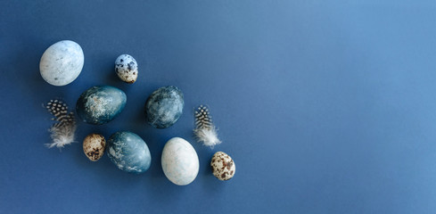 Fototapeta na wymiar Beautiful group ombre blue Easter eggs with quail eggs and feathers on a blue background. Easter concept. Border eggs. Copy space for text