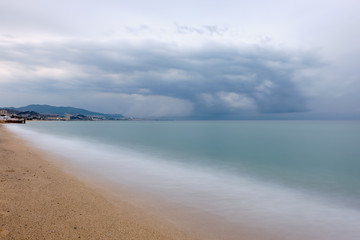 Long exposure on the beach with golden sand and a storm in the distance, Badalona