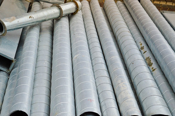 Large iron metal tin corrugated ventilation pipes of large diameter for the industrial construction of ventilation at a construction site during the repair