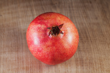 A large bright pomegranate lies on a white oak kitchen board and is illuminated by two light...