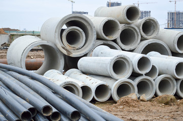 Large black plastic and concrete stone cement sewer plumbing pipes for the construction of water pipes or sewers at a construction site during the repair