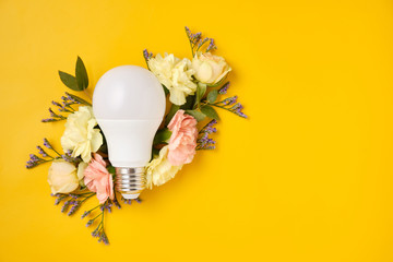 Energy Saving LED Lamp with Flowers over yellow background. Gree