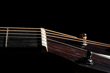 Part of an acoustic guitar close-up, on a black background.