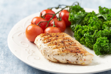 Grilled Chicken Breast with roasted Cherry Tomatoes. Bright wooden background