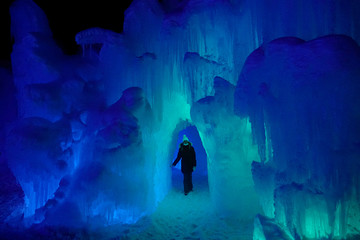 Young woman walks around a spectacular icy cavern in Colorado full of icicles.