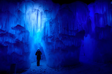 Traveler walks around an icy pillar inside a picturesque icecave in Colorado.
