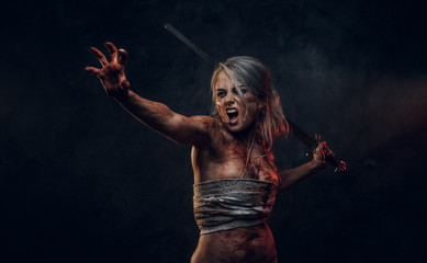 Fantasy woman warrior wearing rag cloth stained with blood and mud holding a sword and rushes into battle with a furious cry. Studio photo on a dark background with smoke. Cosplayer as Ciri from The