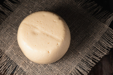 cheese head lies on a rough burlap lying on a rusty surface. dark photo