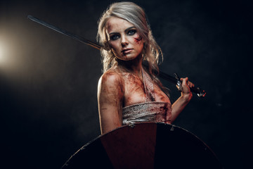 Fantasy woman warrior wearing rag cloth stained with blood and mud, holding sword and shield....