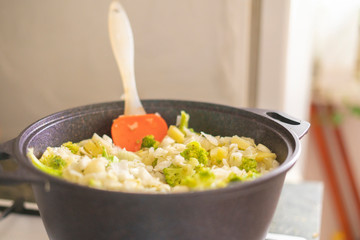 a big pilaf pan bowl with mix of vegetables , cooking on the kitchen