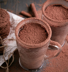 Two cups of hot chocolate on a wooden table with oatmeal cookies and chocolate