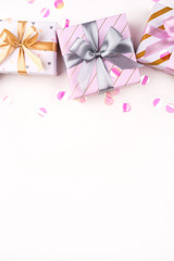 Gift boxes with bows and confetti on a white background. Flat lay composition. Birthday, christmas, wedding or another holiday concept.