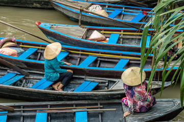 Fototapeta na wymiar Two women resting on their wooden boats in the Mekong Delta