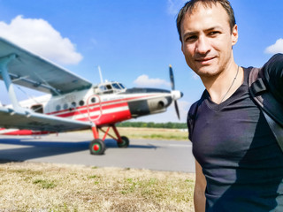 Portrait of serious attractive young man near small airplane
