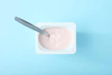 Tasty yogurt in a plastic glass on a colored table top view. Place to insert text. Useful snack.
