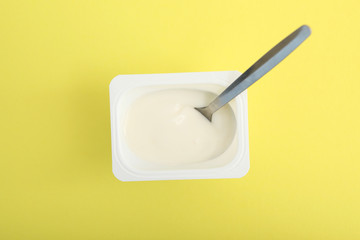 Tasty yogurt in a plastic glass on a colored table top view. Place to insert text. Useful snack.