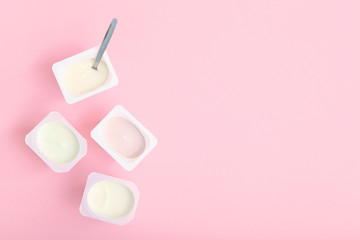 Tasty yogurt in a plastic glass on a colored table top view. Place to insert text. Useful snack.