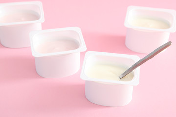 Tasty yogurt in a plastic glass on a colored table. Place to insert text. Useful snack.