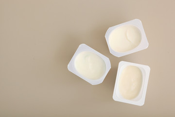 Tasty yogurt in a plastic glass on a colored table top view. Place to insert text. Useful snack.