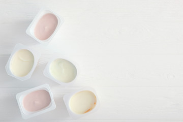 Tasty yogurt in a plastic glass on a colored table top view. Place to insert text. Useful snack.