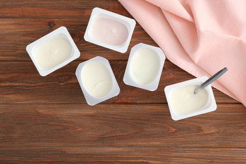 Tasty yogurt in a plastic glass on a colored table top view. Place to insert text. Useful snack.