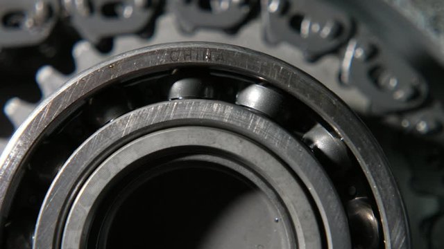 Revolving ball bearing fixed on a large cogwheel with teeth and pulling chain