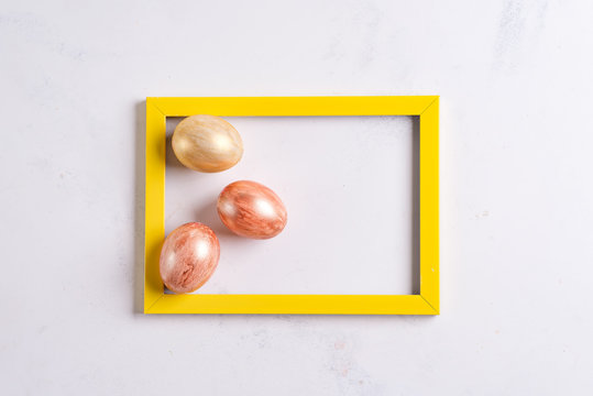 Easter Greeting Card And Golden Eggs In The Yellow Photo Frame On A Marble Background