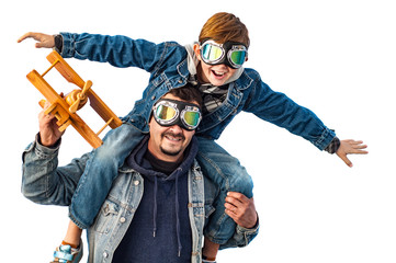 Dad and son wearing pilot glasses imitate pilots, holding a wooden plane in their hands. Isolate © alonaphoto