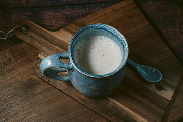 top view of blue rustic cup of coffee with milk on wooden table