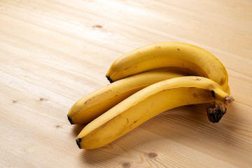 Ripe yellow bananas on a wooden table.