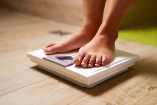 Woman standing on weight scale in bathroom