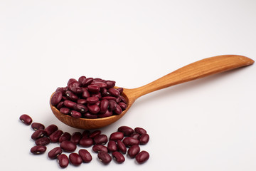 Red beans in wooden spoon, isolated.