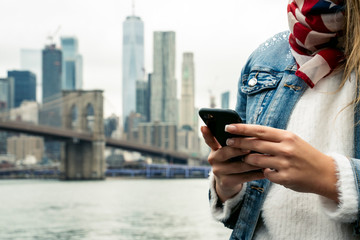 attractive woman using her smartphone with the New York skyline in the background