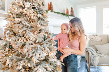 Mother Holding baby daughter by christmas tree