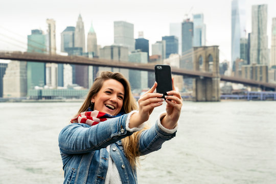 attractive woman using her smartphone with the New York skyline in the background