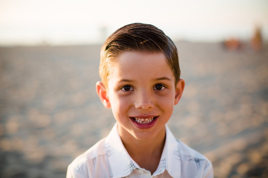 Young Boy Smiling at Camera on Beach at Sunset